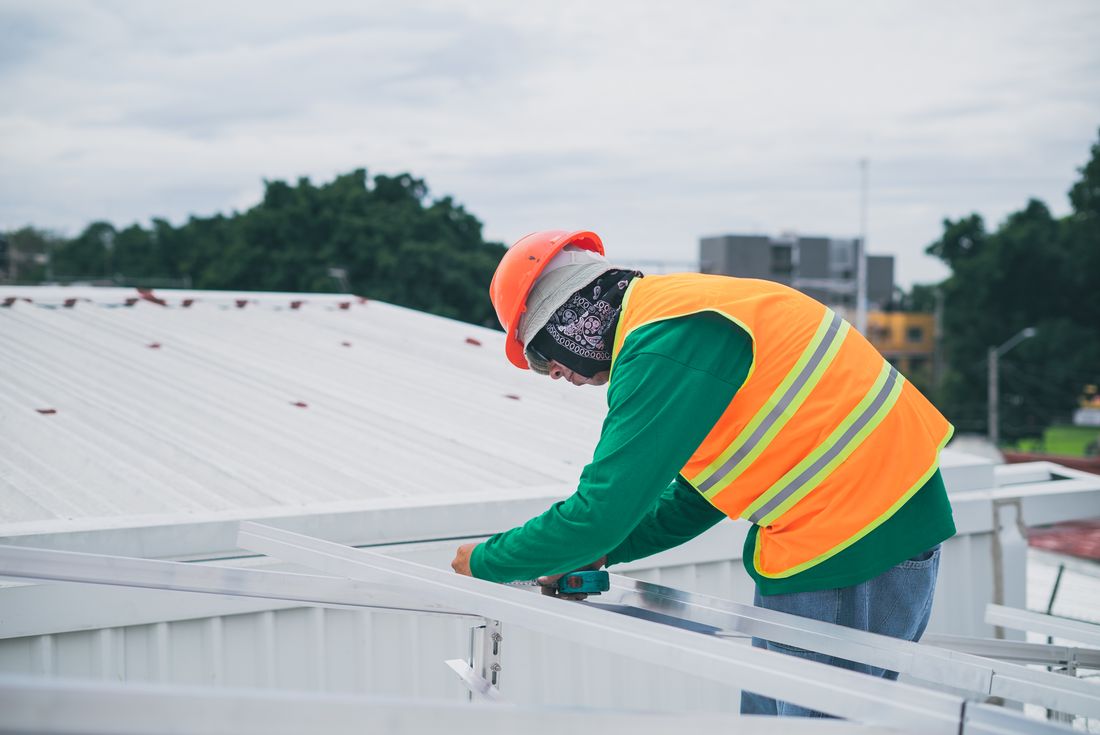 An installer in safety gear working on a rooftop installation